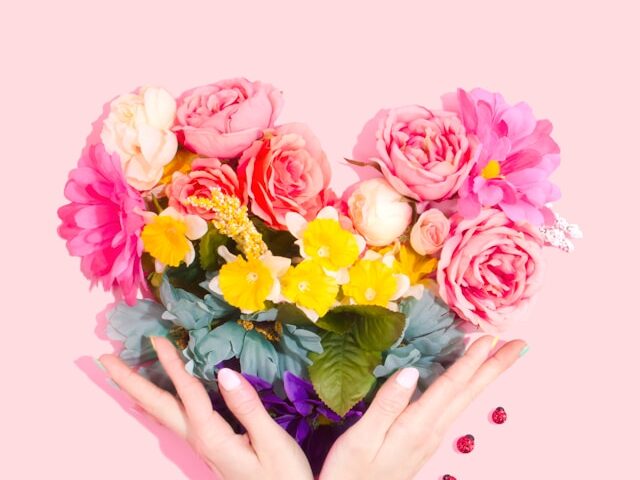 花がハートの形になっていって手で囲んでいる画像