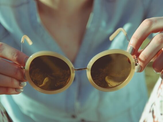 女性がサングラスを持っている画像