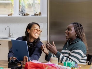 女性二人が家でパソコンを見ながら笑っている画像